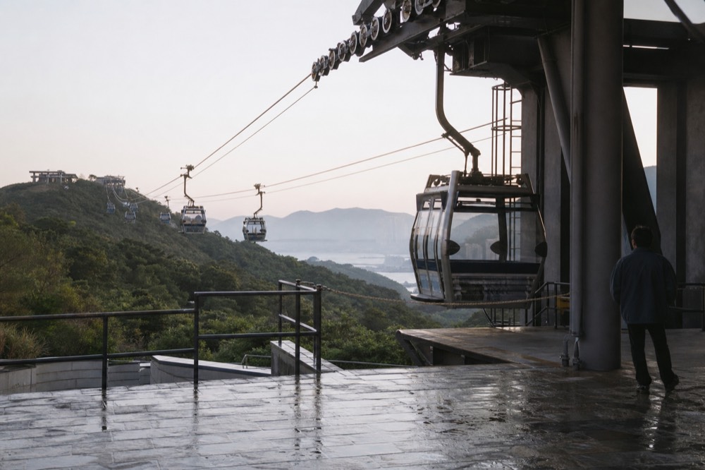 Cable car cabins arriving at a hillside terminal in early morning light, no text, no logos, no people
