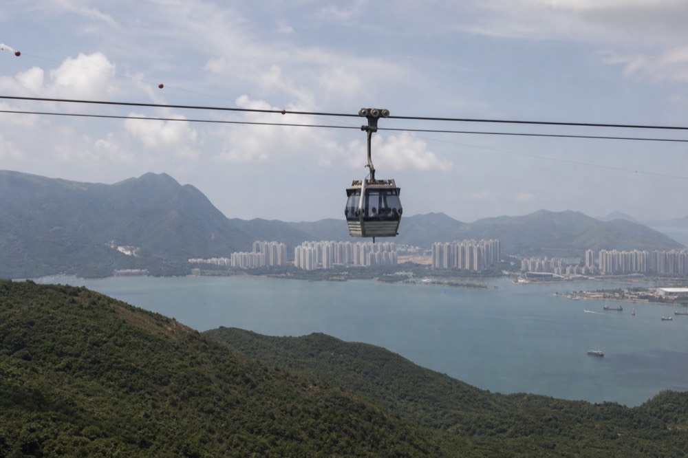 A cable car cabin travelling above green slopes and water, no text, no logos, no people