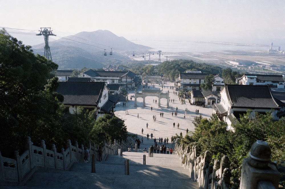 The plaza and monastery rooftops below the Buddha seen from the top of the steps, no text, no logos, no people