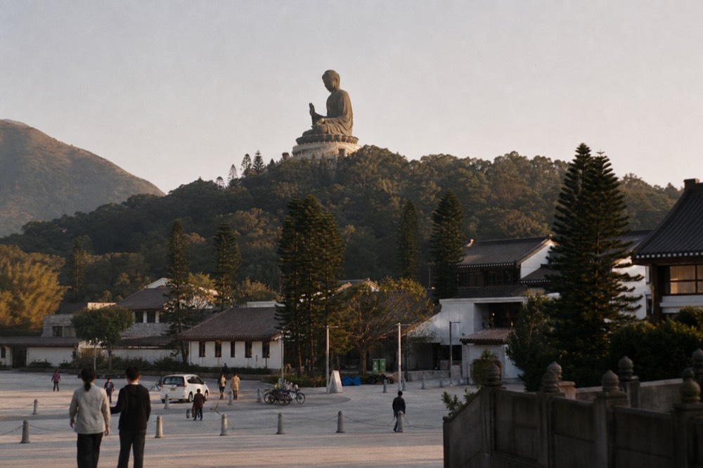 The Tian Tan Buddha statue seen across the Ngong Ping plateau from a distance, no text, no logos, no people