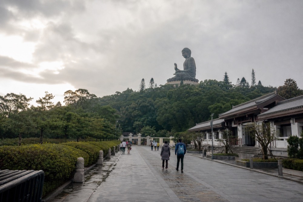 The Tian Tan Buddha seen from the approach path across the Ngong Ping plateau, no text, no logos, no people