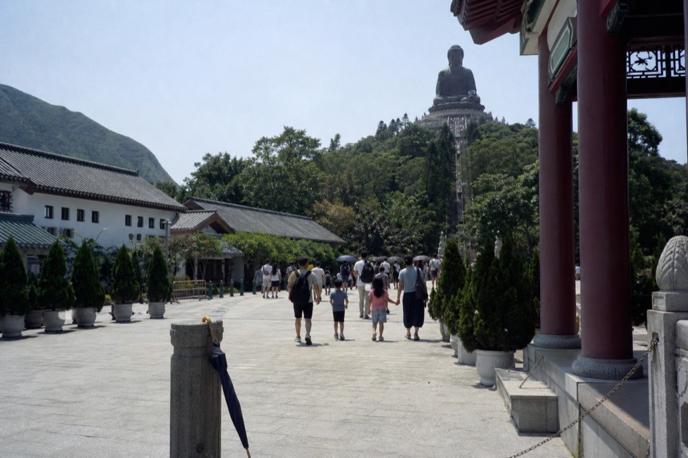 Families walking the plaza toward the Tian Tan Buddha steps at Ngong Ping, no text, no logos, no people