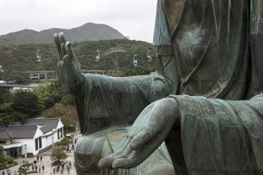 Close view of the bronze robes and hands of the seated Tian Tan Buddha statue, no text, no logos, no people
