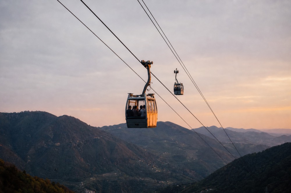 Two cable car cabins travelling on the ropeway above Lantau hills and sea, no text, no logos, no people.
