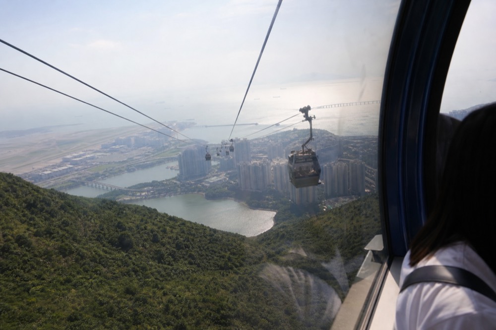 Aerial view of Hong Kong International Airport runways beside green hills, no text, no logos, no people