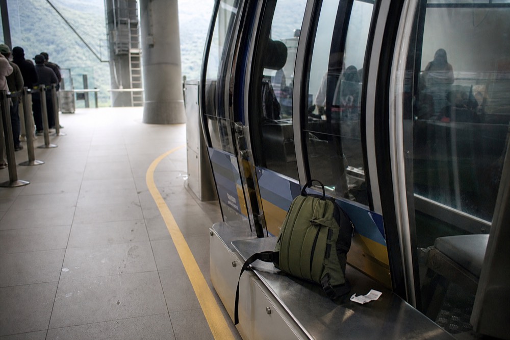 Small daypack and luggage tag beside a cable car cabin door, no text, no logos, no people
