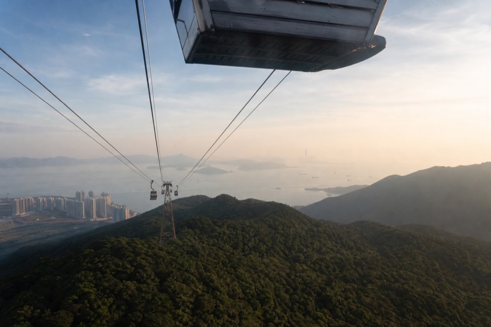 Cable car cabin over Lantau hills with Disneyland castle in distance, no text, no logos, no people