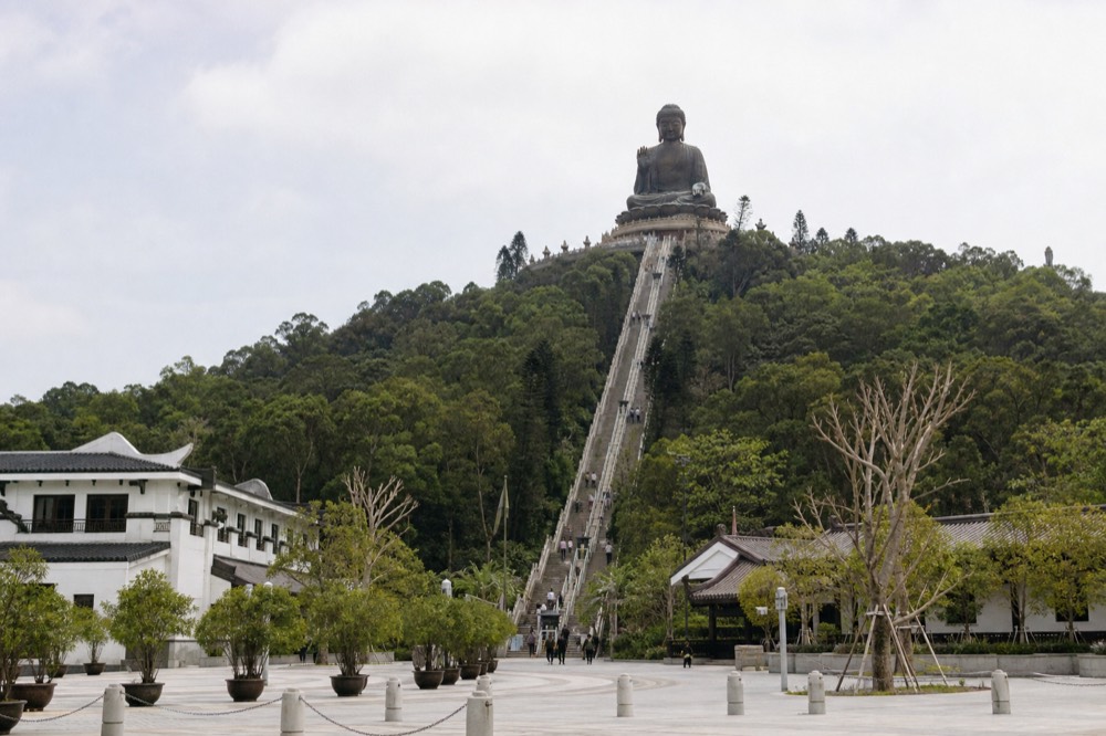 The Tian Tan Buddha seen from a distance across the Ngong Ping plateau, no text, no logos, no people