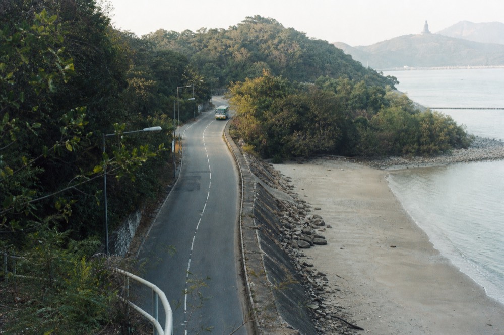 Narrow coast road winding along a shoreline with sand and trees, no text, no logos, no people