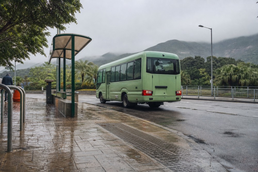 Bus stop beside a beach road with sand and hills in the distance, no text, no logos, no people