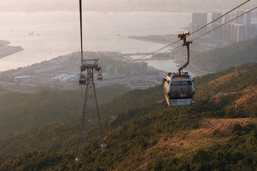 A cable car cabin descending toward the Tung Chung terminal in late afternoon light, no text, no logos, no people.
