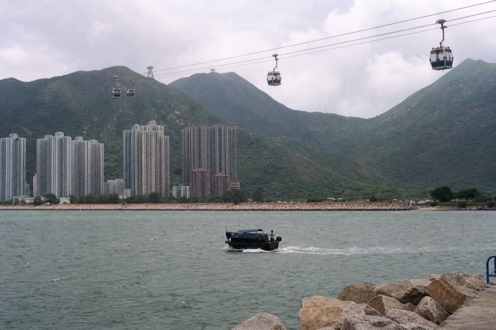 Cable car cabins crossing the water above Tung Chung Bay towards the Lantau hills, no text, no logos, no people