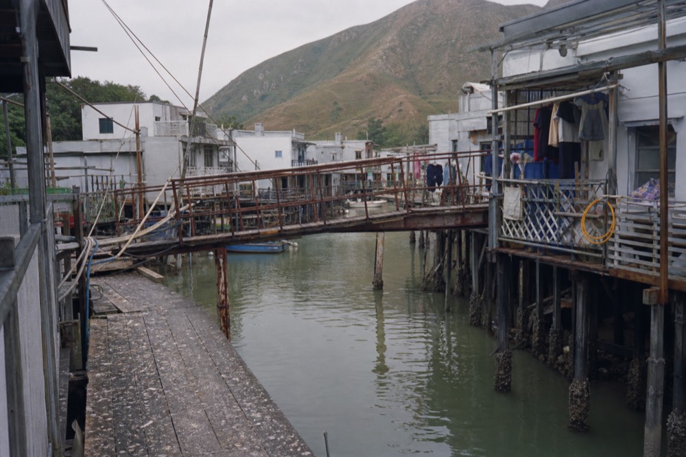 Traditional stilt houses raised on wooden piles above a water channel in Tai O fishing village, no text, no logos, no people